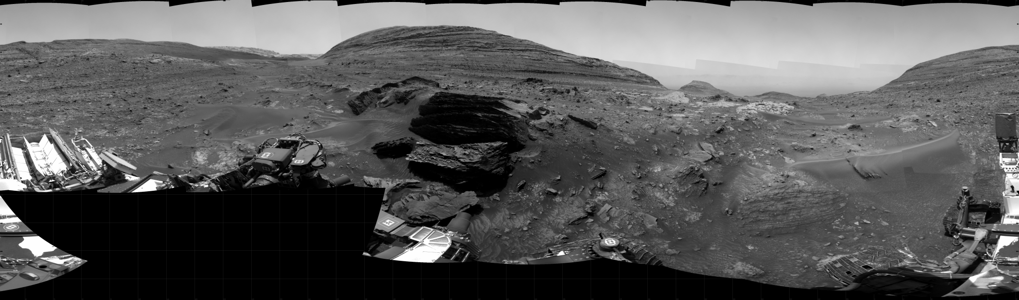 A grayscale panoramic image of the Martian surface shows booth sky and ground well-lit.