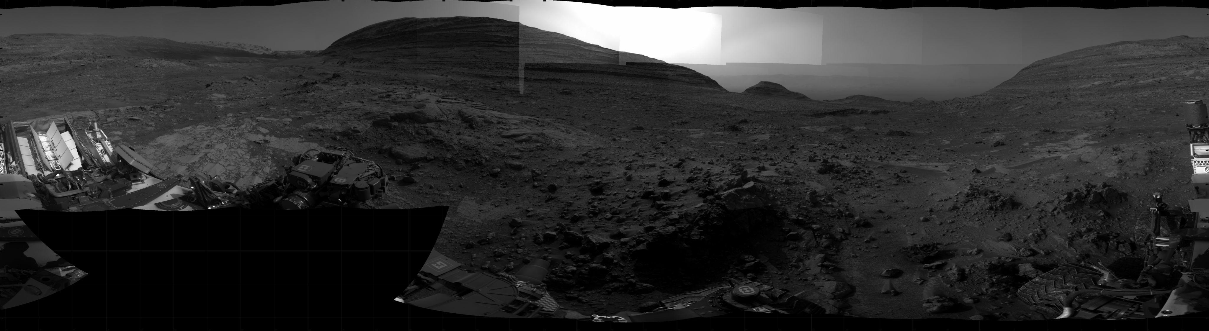 A grayscale panoramic image of the Martian surface shows booth sky and ground.