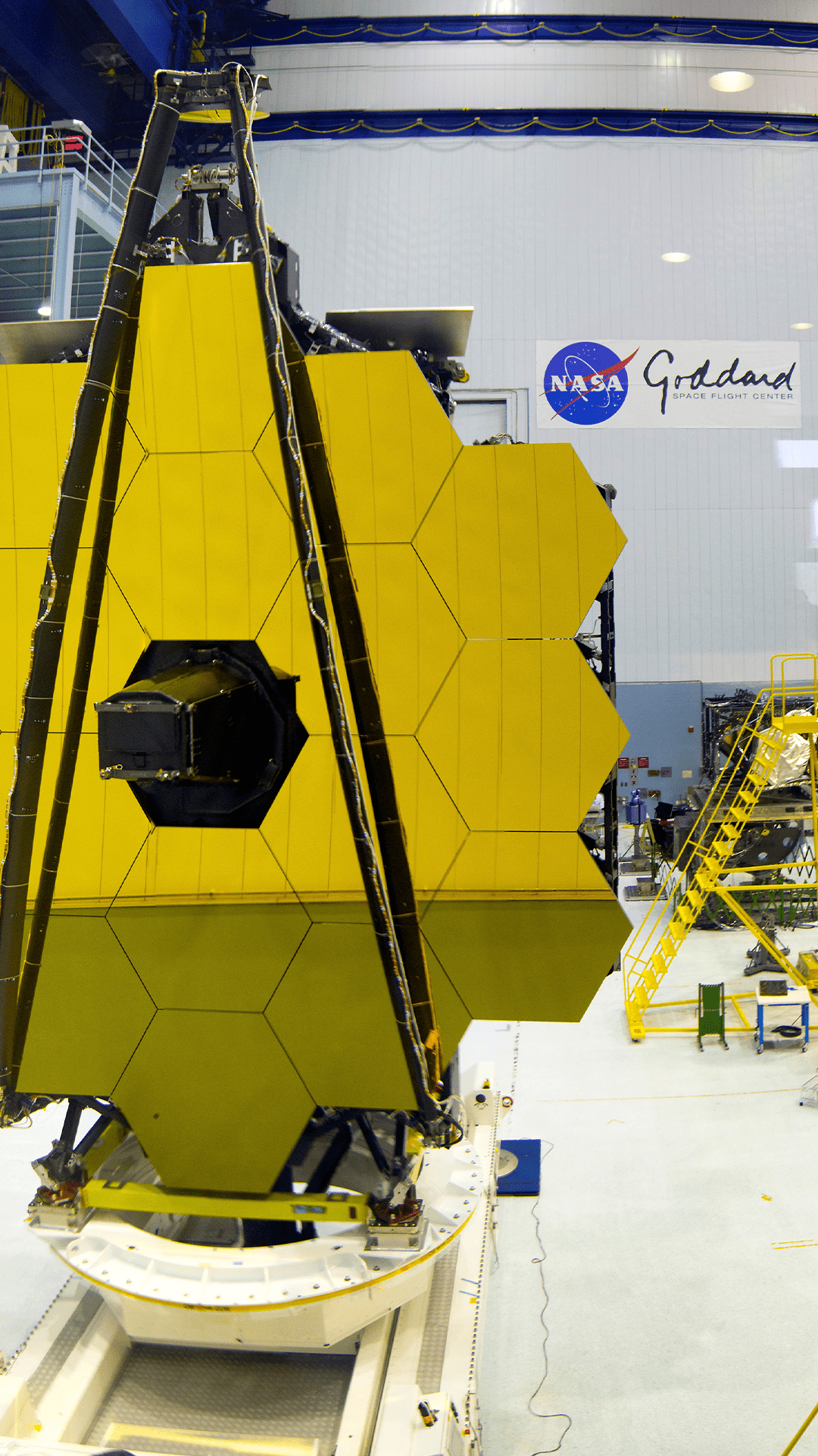 Vertical view of the Goddard Clean Room with the Webb Primary Mirror on test stand in left side foreground with other clean room structures in the background.