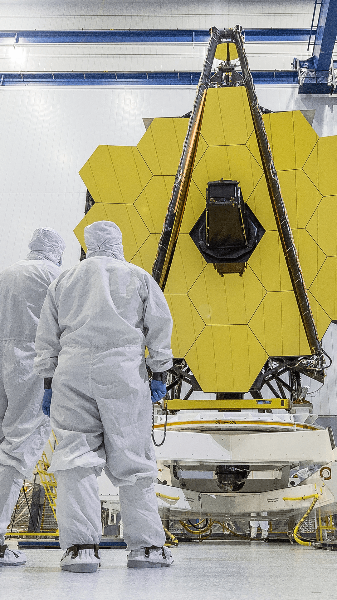 Vertical ground-level view of Webb Primary Mirror with technicians in foreground in the Goddard Clean Room.