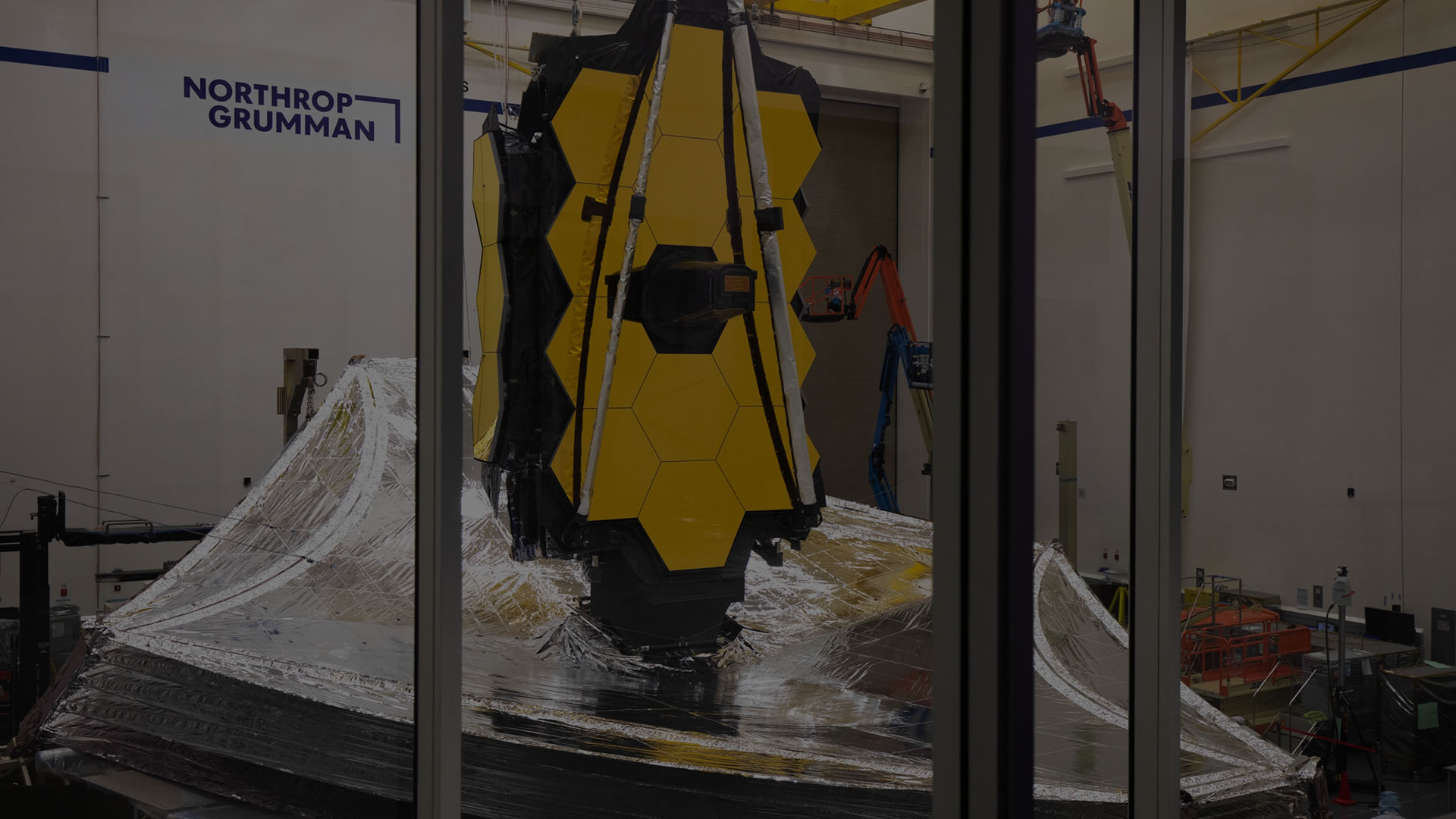 Full darkened view of Webb with sunshield and mirrors with two mirror wings folded in the Northrop Grumman Clean Room.