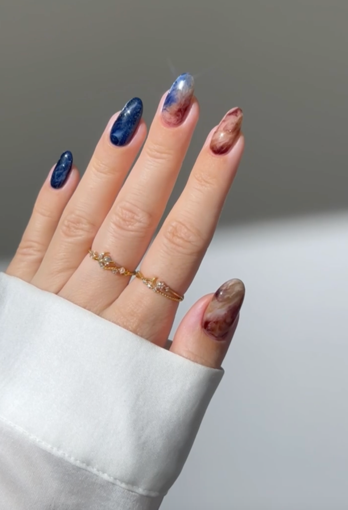 Fingers with nails painted with colors and art symbolic of the Europa Clipper mission.