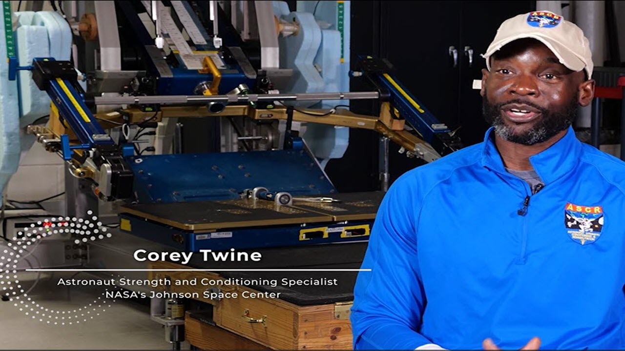 Screenshot from video featuring SME Corey Twine sitting in front of his exercise equipment with his name and title, Astronaut Strength and Conditioning Specialist from NASA’s Johnson Space Center.