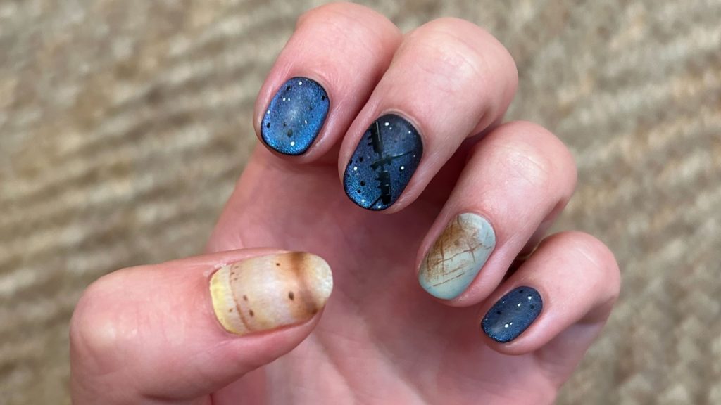 Fingers with the nails painted in colors honoring the Europa Clipper mission.