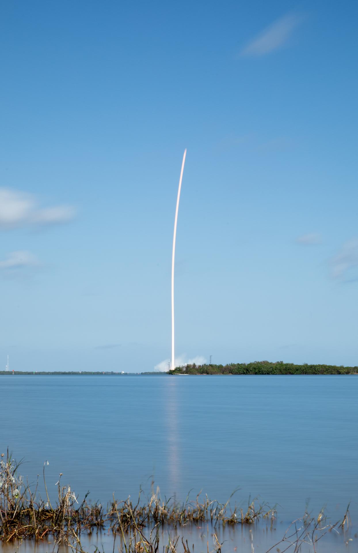 A white streak of smoke against a blue Florida sky shows the path Europa Clipper took as it left the launch pad.