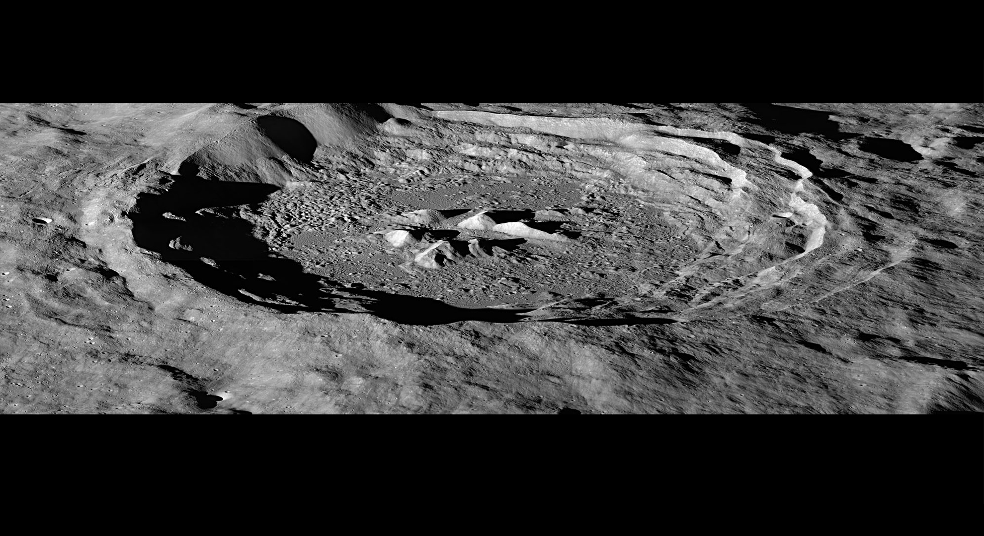 Hayn crater in black and white, viewed obliquely. The left side is ringed in shadow and the craters central peaks are prominent. This image has "letterboxing" style black strips across the top and bottom to size the image appropriately for the slideshow which are not part of the image itself.