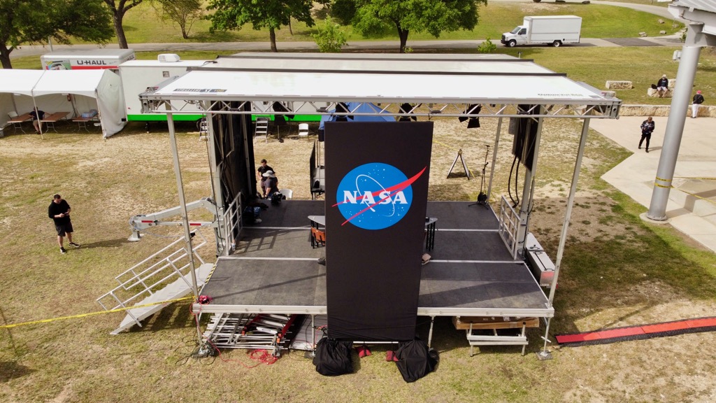 NASA broadcast stage with a large NASA banner sits in Louise Hays Park in Kerrville, TX.