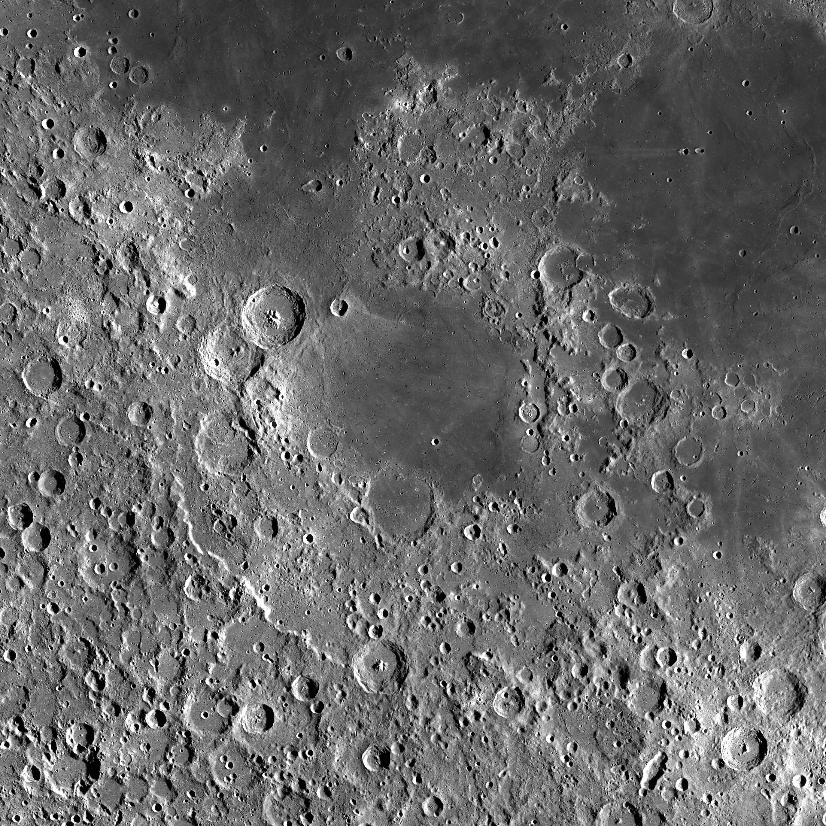 Gray and white image of the cratered and pitted surface of the moon. The craters surround a circular, relatively undisturbed area.