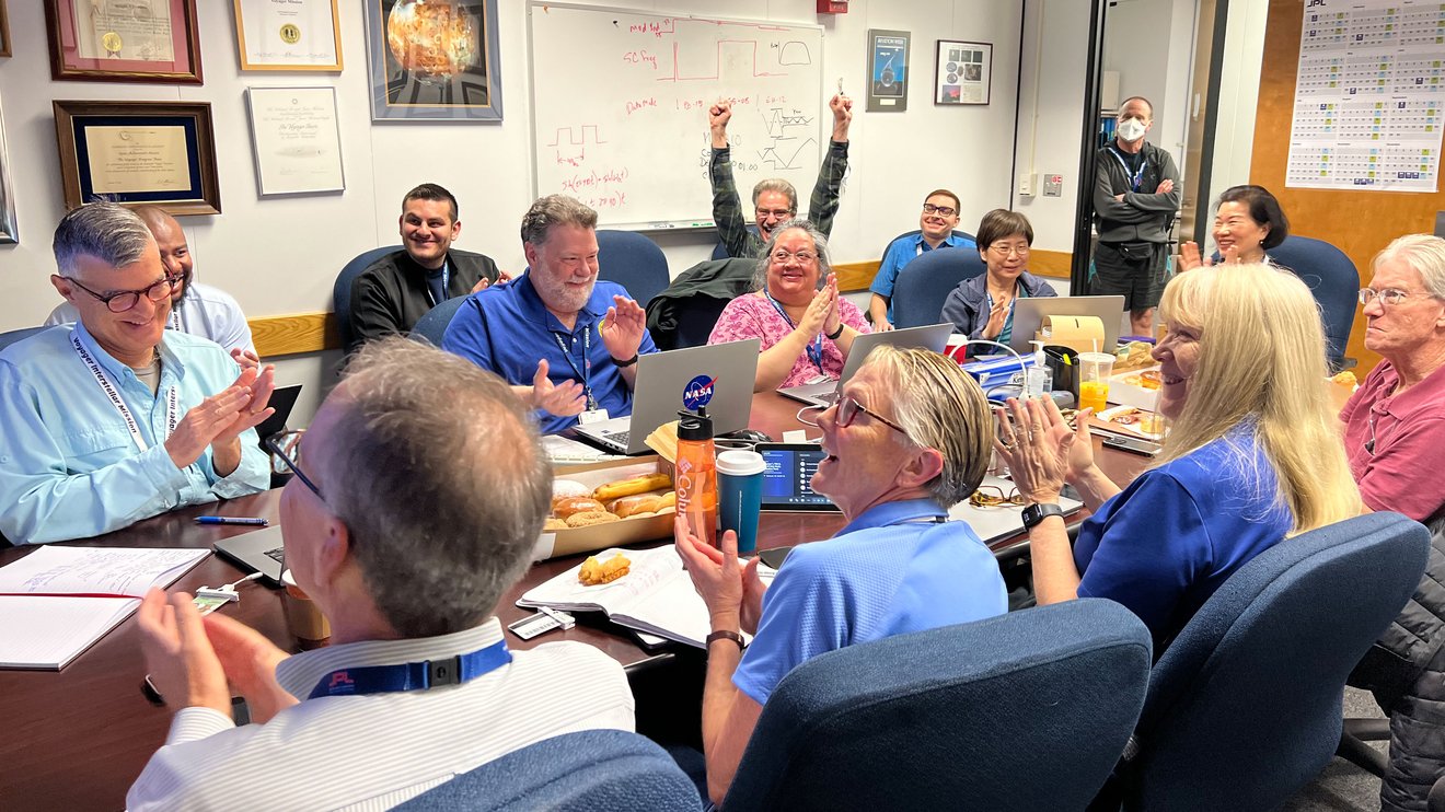 People sitting around a table indoors cheer.