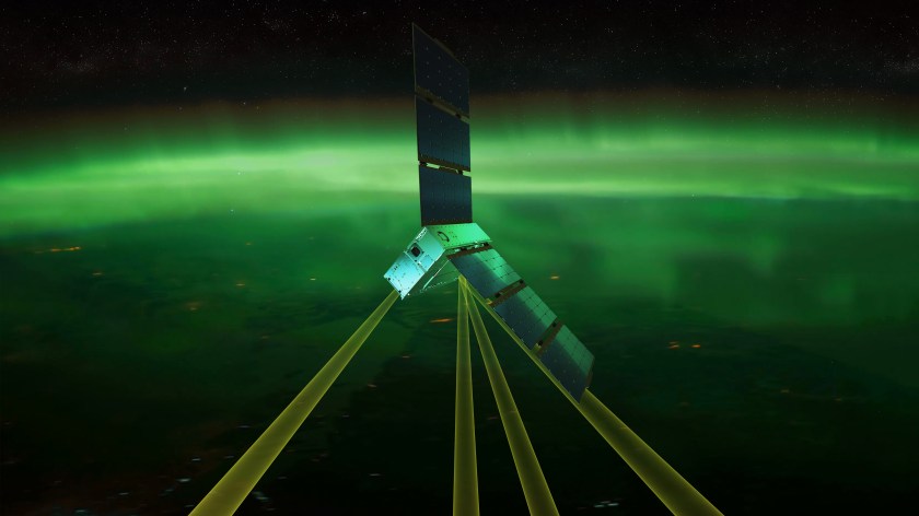 A small, rectangular satellite with two large solar arrays appears in Earth orbit above green-colored auroras. Four yellow-colored beams extend downward from the spacecraft toward the auroras. 
