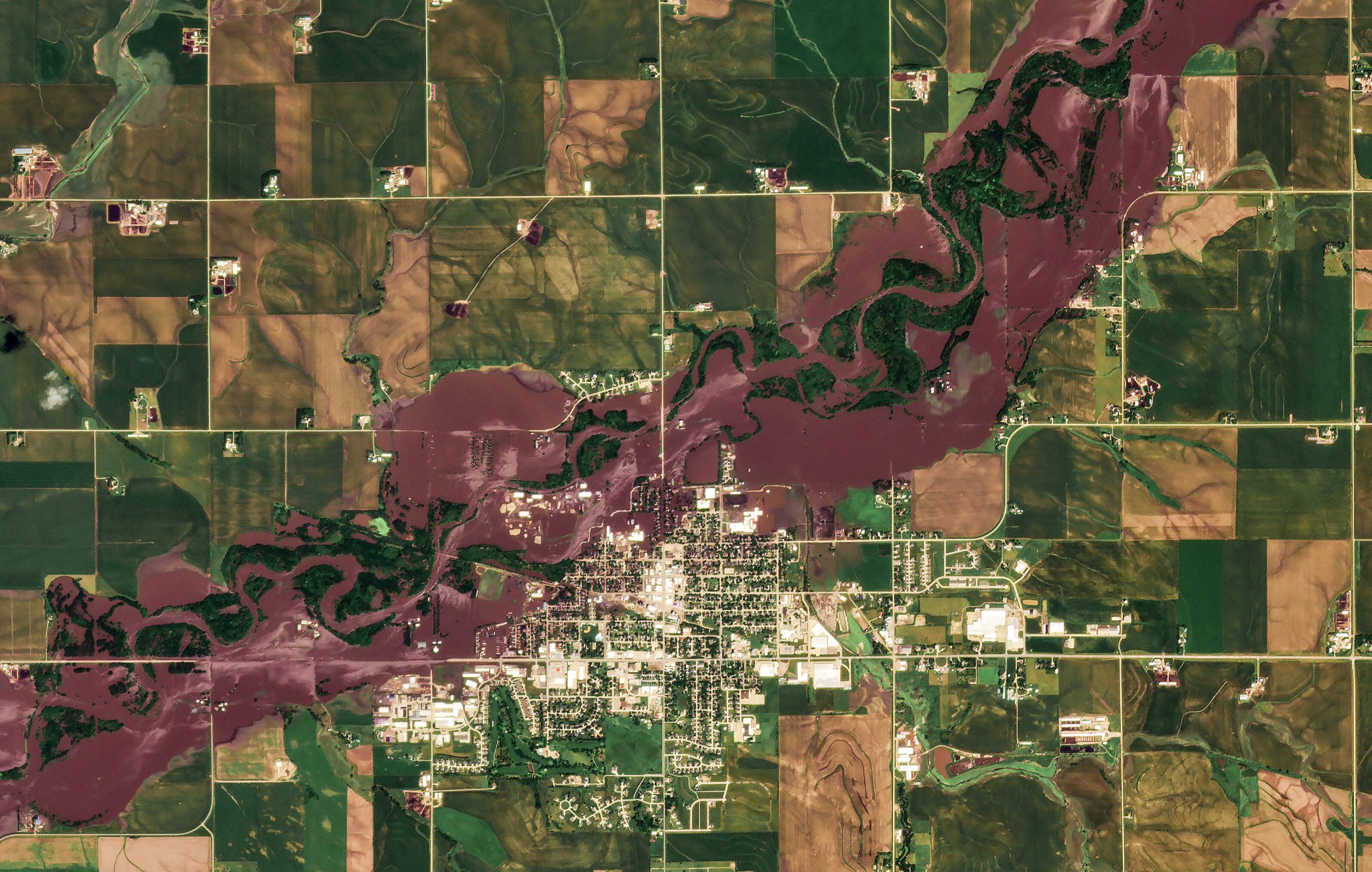 Aerial view of Rock Valley with floodwaters covering large parts of the town after the Rock River overtopped its levees; surrounding agricultural fields show visible crop damage.