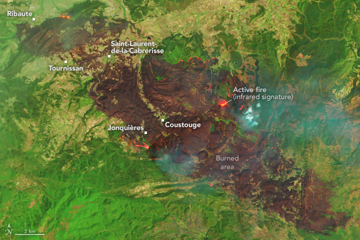 A false-color satellite image shows a detailed view of the burned area, which appears as a brown patch running diagonally across the scene. It is surrounded by green vegetation. Several red spots dot the burned area.