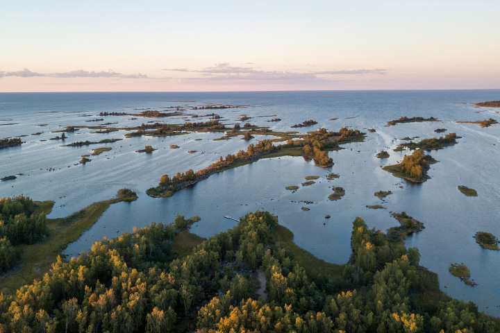 Photograph taken at sunset of tiny islands in the Kvarken Archipelago. Open ocean extends to the horizon.