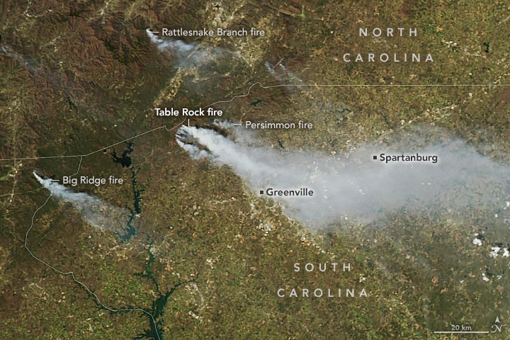 A satellite image shows a wide view of parts of Georgia, South Carolina, and North Carolina. Smoke from fires burning in each state is being blown toward the east-southeast.