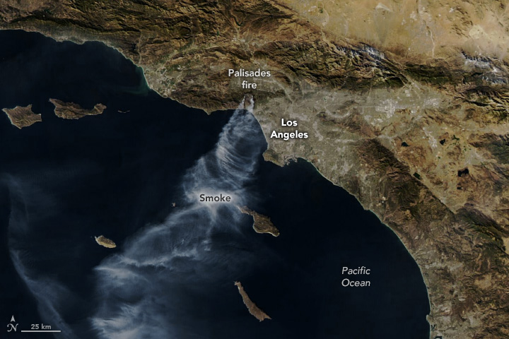 A satellite image of the southern California coast around Los Angeles. Light gray plumes of smoke stream south from the land over the ocean.