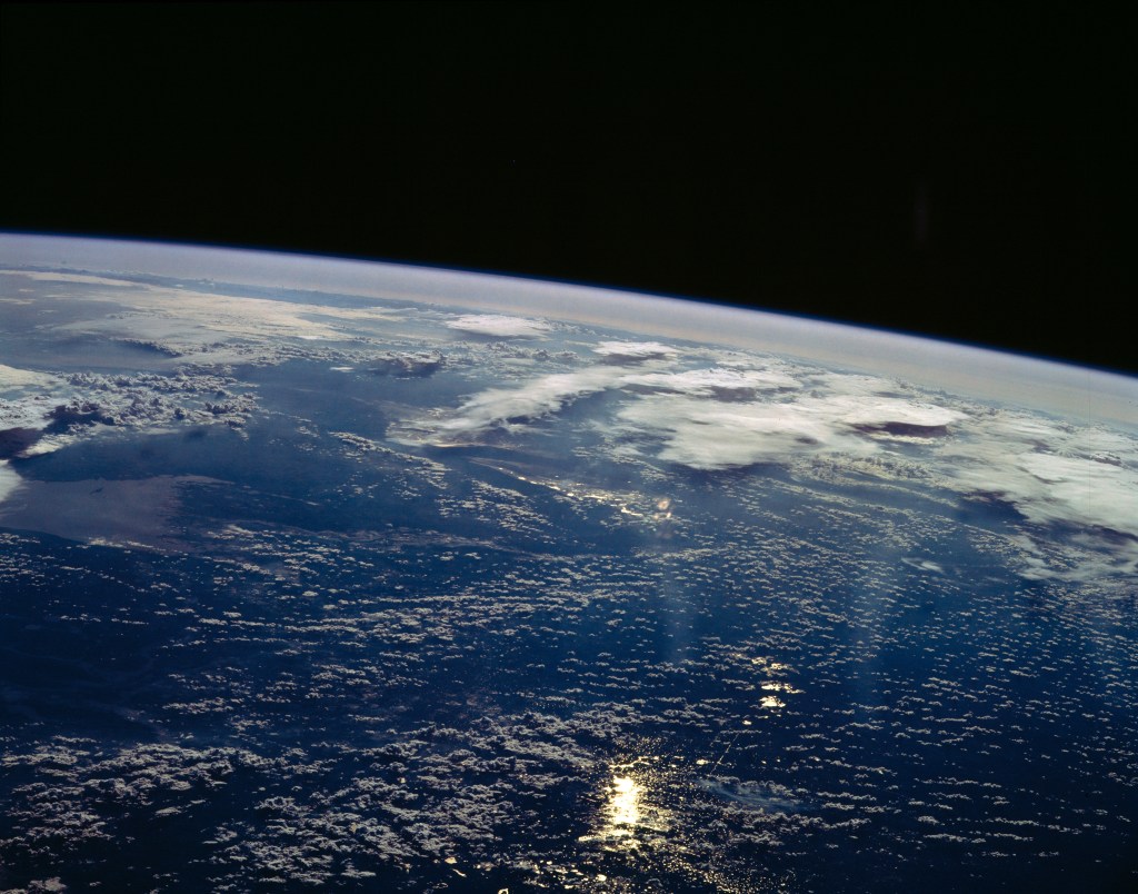 View west into sun glint off the Rio Salado, Saladillo, and Parana Rivers in Argentina. The Space Shuttle nadir is about 28 degrees north latitude and 57 degrees west longitude. The Andes Mountains are barely visible on Earth's limb. Thunderstorms along the eastern edge of the Andes are typical of this time of year (Southern Hemisphere summer), with anvils moving to the east from the core of the storm.